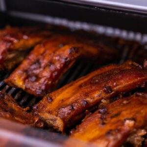 Imagem de costela assada na Airfryer, coberta com molho barbecue. A costela é suculenta e tenra, com uma crosta crocante. O molho barbecue é doce e picante, complementando perfeitamente o sabor da costela.