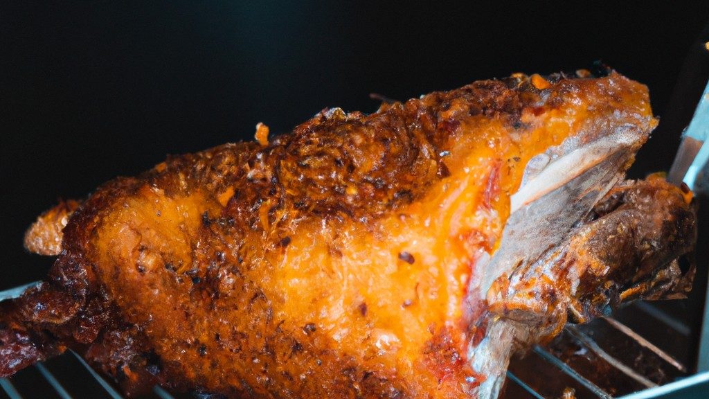 Imagem de uma costela de porco assada e glaceada em uma cesta de fritadeira com fumaça saindo dela. A costela está coberta com um molho barbecue escuro e tem uma crosta crocante.