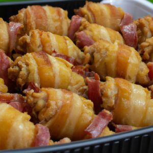 Foto de coxas de frango assadas com bacon na airfryer, servidas em um prato com rodelas de limão e ervas frescas. As coxas de frango estão douradas e crocantes, com o bacon adicionando um toque salgado e defumado.