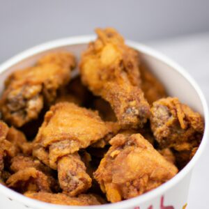 Coxa de frango crocante e dourada cozida na airfryer, apresentada em um prato branco com um raminho de alecrim ao lado. A pele do frango está perfeitamente crocante, enquanto a carne por dentro permanece suculenta e macia.