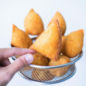 Imagem de uma coxinha de asa frita ao ar com batata frita, servida em um prato com um lado de molho. A coxinha de asa é crocante e dourada, e a batata frita é fina e crocante.