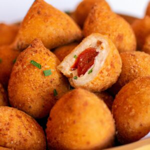 Imagem de coxinhas da asa crocantes e douradas cozidas em uma airfryer. As coxinhas são temperadas com um delicioso tempero caseiro, composto por ervas e especiarias, dando um sabor irresistível.