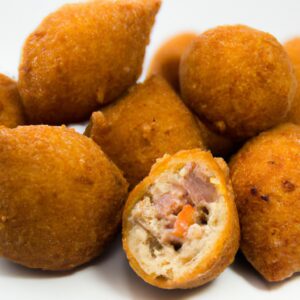 Imagem mostrando coxinhas de frango assadas em uma assadeira, sem pele e cobertas com uma crosta dourada e crocante. As coxinhas são servidas em uma travessa com um ramo de alecrim fresco.