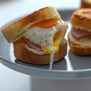 Imagem de um Croque Madame em uma Airfryer. O sanduíche é feito com duas fatias de pão branco, queijo Gruyère derretido, presunto e um ovo frito por cima.