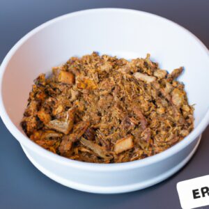 Imagem de uma porção de crumble de maçã vegana recém-assada em uma tigela pequena de cerâmica preta. O crumble é coberto com aveia crocante e nozes picadas e servido com uma colher de sorvete de baunilha vegano. O fundo é uma superfície de madeira escura com um guardanapo de linho branco dobrado ao lado.