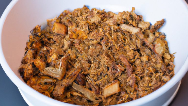 Imagem de uma porção de crumble de maçã vegana recém-assada em uma tigela pequena de cerâmica preta. O crumble é coberto com aveia crocante e nozes picadas e servido com uma colher de sorvete de baunilha vegano. O fundo é uma superfície de madeira escura com um guardanapo de linho branco dobrado ao lado.
