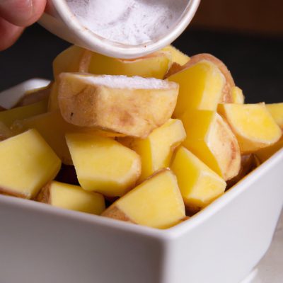 Imagem de um delicioso escondidinho de batata-doce feito na Airfryer. A batata-doce amassada forma a base, coberta por um cremoso purê de mandioca. No topo, uma farofa crocante feita com farinha de milho e temperos. O escondidinho é guarnecido com cebolinha picada e é servido em uma travessa.