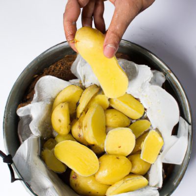 Imagem de um escondidinho de mandioca feito na Airfryer. O prato é composto por uma camada de purê de mandioca, uma camada de carne moída e uma camada de queijo gratinado. O escondidinho está em um prato branco e é acompanhado de uma salada verde.