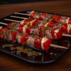 Imagem de espetinhos de carne grelhados na Airfryer, acompanhados de tomates e pimentões assados. Os espetinhos estão dourados e suculentos, enquanto os legumes estão macios e caramelizados. A imagem transmite o aroma e o sabor apetitosos do prato, sugerindo uma refeição rápida e saborosa.