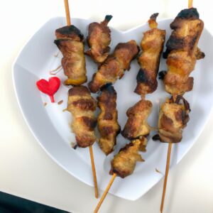 Espetinhos de coração de frango dourados e suculentos preparados na Airfryer. Os espetos de madeira são visíveis, com os corações empilhados firmemente. O fundo é escuro, criando um contraste atraente com os espetos.