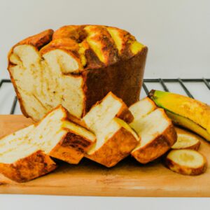 Uma fotografia de um pão de banana caseiro cozido em uma airfryer. O pão é marrom dourado e tem uma crosta crocante. É coberto com nozes e bananas fatiadas.
