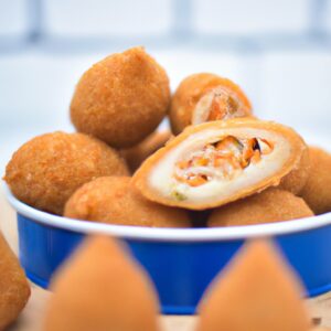 Uma imagem de coxinhas de frango crocantes e douradas preparadas em uma airfryer. As coxinhas são recheadas com frango desfiado temperado e cobertas com farinha de rosca.