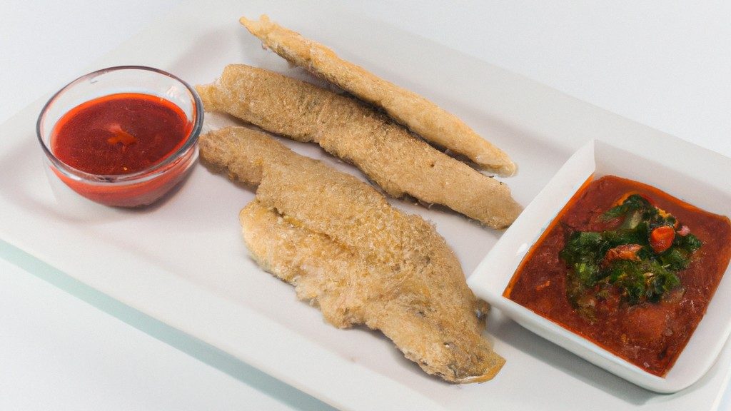 Imagem de um filé de peixe empanado e frito em uma fritadeira Airfryer. O peixe é servido em um prato com uma fatia de limão e um raminho de salsa.