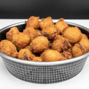 Foto de filetes de peixe empanados crocantes cozidos em uma fritadeira. Os filetes são dourados e têm uma crosta escamosa. Eles são servidos em um prato com fatias de limão e um molho tártaro.