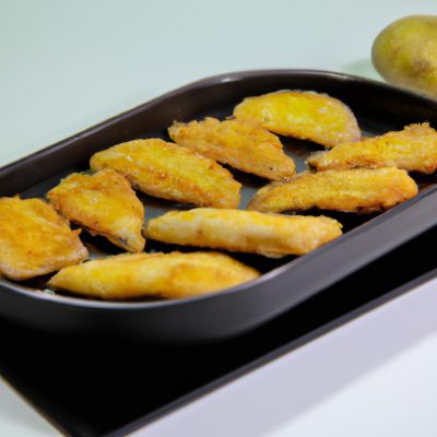 Um prato de filetes de peixe empanados dourados e crocantes, cozidos em uma Airfryer. Os filetes são colocados sobre uma cama de batatas fritas crocantes e polvilhados com limão fresco e salsa.