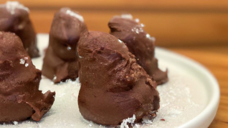 Imagem de uma cesta de fritadeira cheia de fudge de varinha de chocolate, com os topos salpicados de granulado de arco-íris. O fudge é marrom escuro e brilhante, com uma textura lisa e cremosa. É cortado em quadrados e disposto em linhas ordenadas na cesta. O fundo é branco, com o texto 