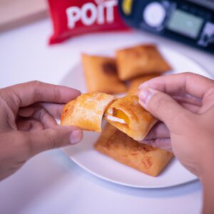 Imagem de um Hot Pocket sendo cozido em uma Air Fryer. O Hot Pocket está dourado e crocante, e a Air Fryer está posicionada em uma bancada de cozinha.