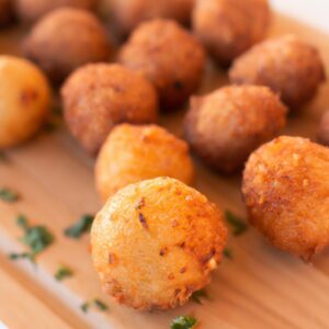 Imagem de uma airfryer cheia de kibes Sadia prontos para serem fritos. O fundo é uma superfície de madeira e a imagem tem um tom quente.