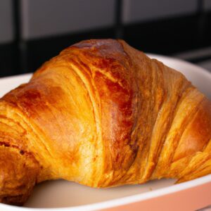 Imagem de croissants quentes e crocantes cozidos em uma airfryer, com um fundo de papel manteiga e uma pitada de açúcar de confeiteiro por cima.