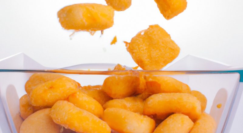 Imagem de uma porção de estalinhos de queijo em uma tigela, feitos na airfryer. Os palitos são dourados e crocantes, com uma textura fofa por dentro. Eles são servidos com um molho de tomate para mergulhar.
