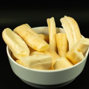 Imagem de mandioca frita em uma Airfryer. A mandioca está cortada em palitos e tem uma cor dourada crocante. Ela está disposta em uma cesta de Airfryer e o fundo é visível.