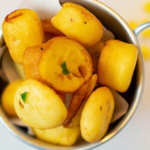 Imagem de mandioquinhas cortadas em palitos, douradas e crocantes, servidas em um prato. As mandioquinhas foram preparadas na Airfryer, uma fritadeira sem óleo, e estão acompanhadas de um molho de tomate ao lado.