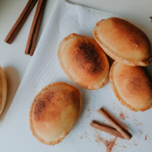 Imagem de uma massa de pastel frita na airfryer, polvilhada com açúcar e canela. A massa está dourada e crocante, e o açúcar e a canela criam uma cobertura doce e aromática.