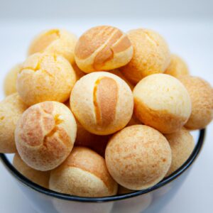 Imagem de mini pães de queijo crocantes e dourados, feitos na Airfryer. Esses aperitivos caseiros são pequenos, redondos e têm uma crosta crocante com um interior macio e queijo. Eles são perfeitos para lanches, festas ou acompanhamentos.