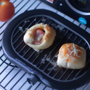 Imagem de uma mini pizza redonda cozida em uma airfryer. A pizza tem uma crosta dourada e está coberta com molho de tomate, queijo mussarela e pepperoni.