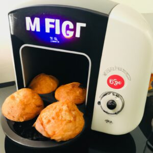 Imagem de muffins de frango recém-assados em forminhas de papel, colocados sobre uma grelha dentro de uma Airfryer. Os muffins são dourados e crocantes por fora, com um interior macio e suculento.