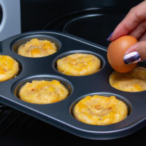 Imagem de muffins de omelete dourados e fofos feitos na Airfryer, servidos em um prato com salsa e pimentão vermelho picado. Os muffins são mostrados de lado, revelando o interior macio e esponjoso.