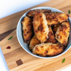 Imagem de Nuggets de Atum na Airfryer prontos, empanados e dourados em um prato branco com um ramekin de molho ao lado.