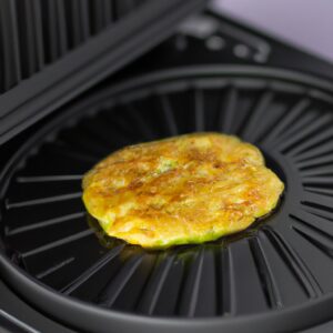 Imagem de uma omelete de abobrinha frita ao ar, cortada em fatias e servida em um prato. A omelete é dourada e crocante por fora e macia e suculenta por dentro.