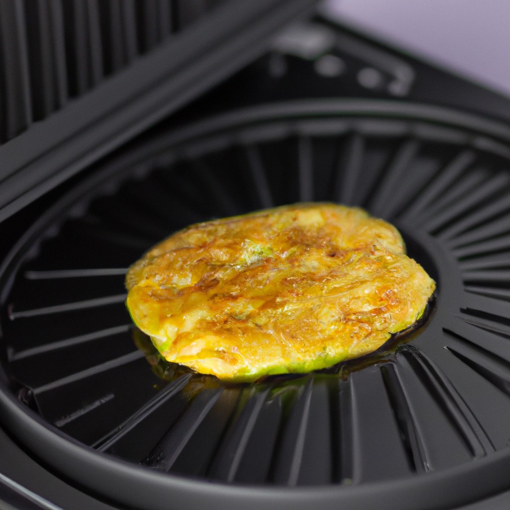 Imagem de uma omelete de abobrinha frita ao ar, cortada em fatias e servida em um prato. A omelete é dourada e crocante por fora e macia e suculenta por dentro.