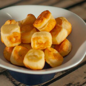 Foto de palitinhos de pão dourados e crocantes fritos em uma Airfryer, acompanhados de um pote de molho para imersão.