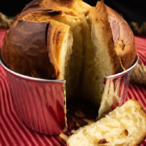 Imagem de um panetone caseiro acabado de fazer, cozido na airfryer, visto de cima. O panetone é dourado e fofo, com uvas passas e frutas cristalizadas visíveis na superfície.