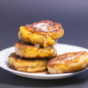 Imagem de panquecas de banana douradas e fofas cozidas em uma airfryer, polvilhadas com calda de bordo e fatias de banana fresca.
