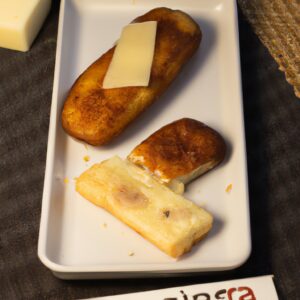 Uma foto de pão de hambúrguer cortado ao meio e recheado com carne moída e queijo derretido, cozido em uma airfryer. O pão está dourado e crocante, e a carne moída está bem cozida e suculenta. O queijo está derretido e borbulhando, cobrindo a carne moída. O fundo é branco e a imagem está focada no pão de hambúrguer.