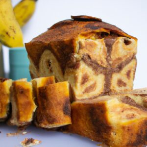 Imagem de um pão de banana dourado e crocante cozido em uma Airfryer, apresentado em uma tigela branca com fatias cortadas ao lado. O pão é polvilhado com nozes picadas e tem uma crosta crocante com um interior macio e úmido.