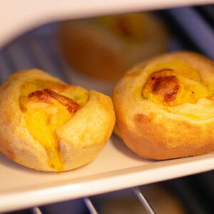 Imagem de pão de forma torrado na airfryer com ovo frito e queijo derretido por cima. A fatia de pão está em um prato branco e há uma faca e um garfo ao lado dela.