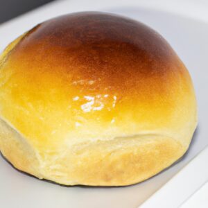 Imagem de pão de forma recheado cozido em uma airfryer. O pão é marrom dourado e tem um recheio cremoso e derretido visível.