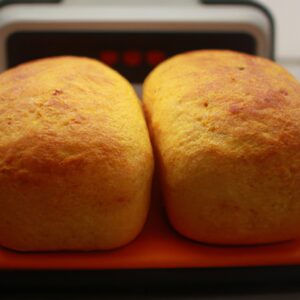 Imagem de pães de minuto dourados e crocantes cozidos em uma airfryer. Os pães são servidos em um prato com manteiga derretida e ervas frescas.