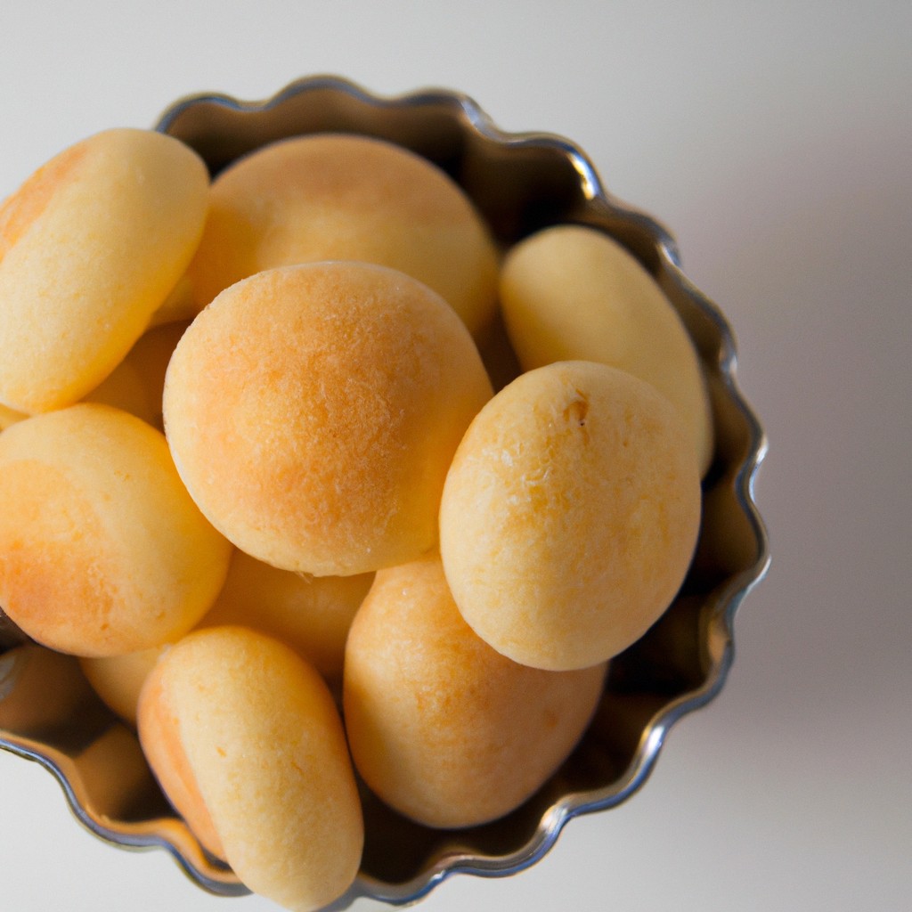 Imagem de pães de queijo de batata-doce recém-assados em uma cesta de fritadeira. Os pães de queijo são dourados e crocantes, com uma textura macia por dentro.