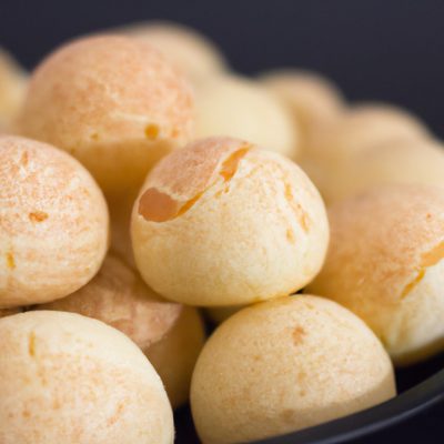Imagem de pães de queijo dourados e crocantes feitos no liquidificador e cozidos na air fryer. Eles estão dispostos em um prato branco e têm uma textura crocante e um interior macio e arejado.
