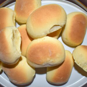 Imagem de pães italianos recém-assados em uma cesta, com uma tigela de azeite ao lado. Os pães são dourados e crocantes, com uma crosta crocante e um miolo macio e arejado. O azeite é claro e dourado, com um aroma fresco e frutado.