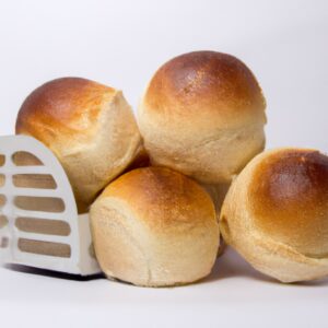 Imagem de pães dourados e crocantes recém-saídos de uma airfryer. A textura crocante do lado de fora contrasta com o interior macio e fofo, criando um pão delicioso e satisfatório.