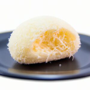 Imagem de um pãozinho de tapioca com queijo. O pãozinho é redondo e dourado, com uma textura crocante e um recheio cremoso de queijo.