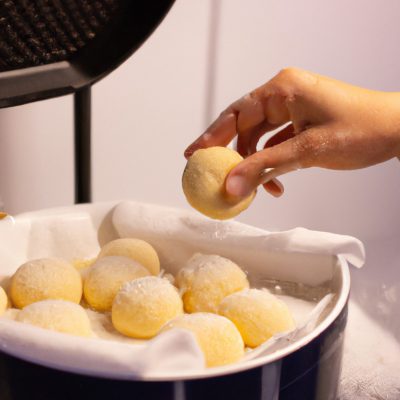 Imagem de pãozinho de tapioca crocante e dourado feito na Airfryer, mostrando sua textura porosa e formato redondo.