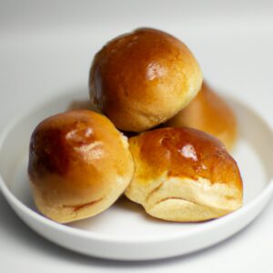 Imagem de pães doces dourados e fofos em uma cesta. Os pães são polvilhados com açúcar e têm uma aparência caseira e apetitosa.