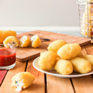 Imagem de um pastel de milho frito em uma airfryer, com recheio dourado e crosta crocante. O pastel é colocado sobre uma grade de metal, com um fundo azul claro.